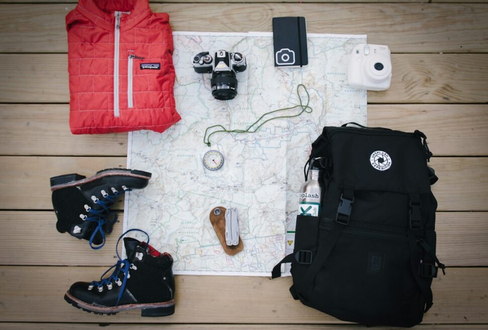 Gorilla trekking packing list - hiking backpack, boots, jacket and camera laid out on a map